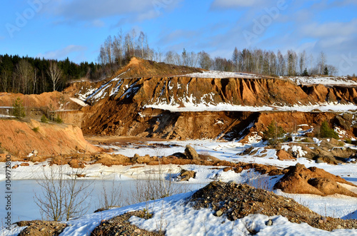 View from the mountain to the red sand in the snow of a small canyon in the Minsk region, Radoshkovichi, the village of Praleski, mining quarry. photo