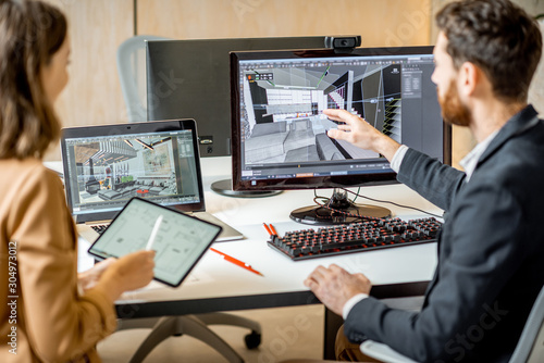 Two creative office employees making interior design on the computer and digital tablet at the modern office of architectural firm. Concept of 3d modeling and digital Interior designing photo