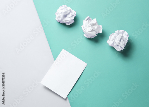 Minimalistic business concept. Crumpled paper balls and empty white leaf on a gray-blue background