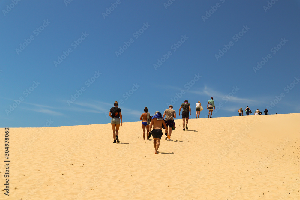 Group of friends walking up a sand dune 2 Group of friends walking up a sand dune 2
