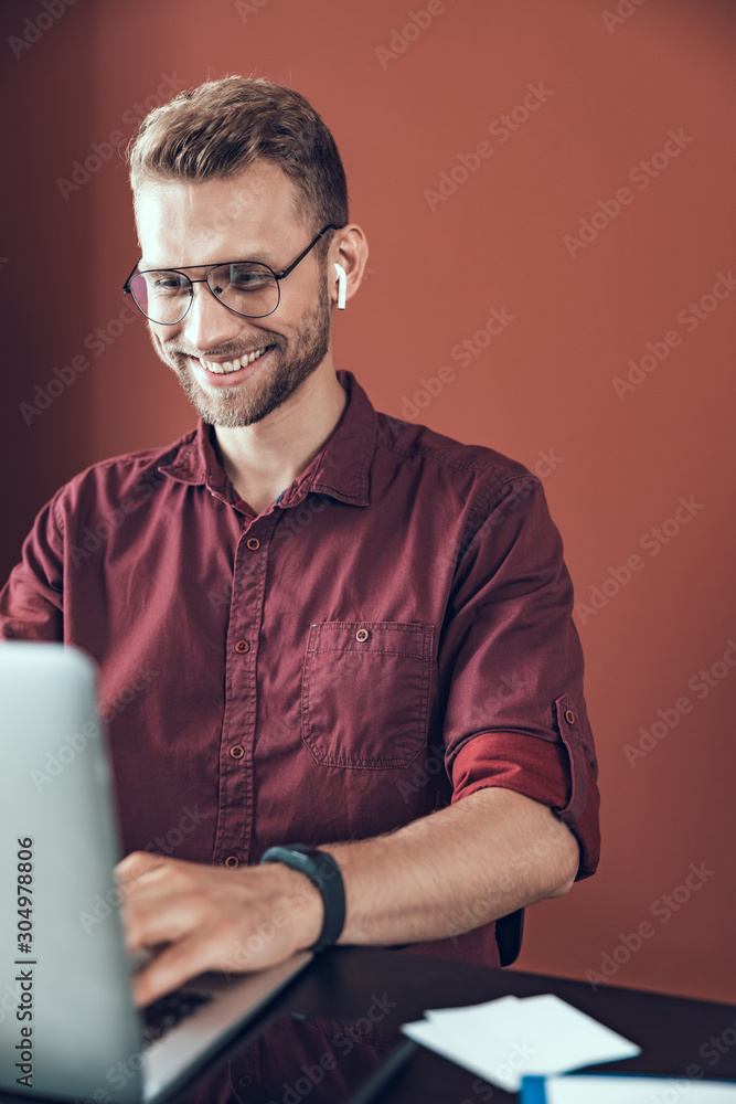 Smiling young man is wearing headphones in office Smiling young man is wearing headphones in office