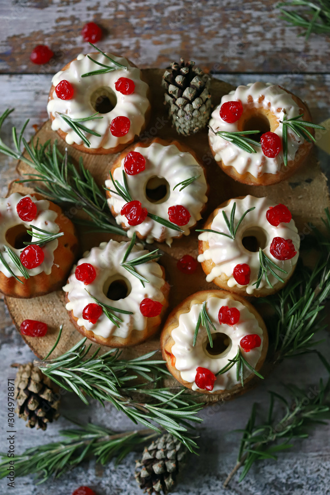 Christmas cakes with white icing, red berries and rosemary. Christmas decoration. Selective focus. Macro.