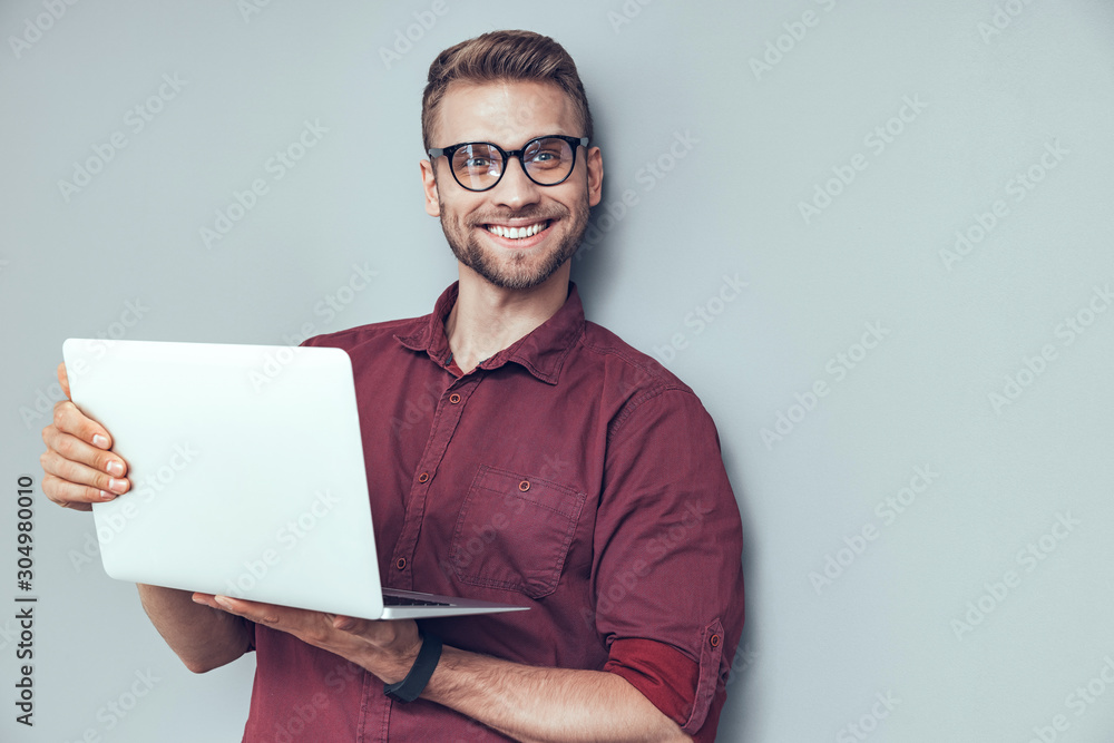 Smiling young guy is using gadget in studio Smiling young guy is using gadget in studio