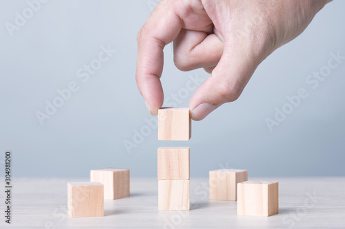 Three Wood Block Cubic stack with Hand on table Blue Tone Background. Free Copy Space.
