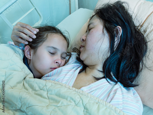 Chinese mother and daughter laying in hosital bed