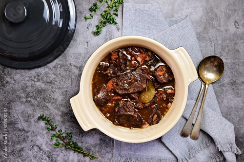 Beef bourguignon in the pot on the grey background, top view