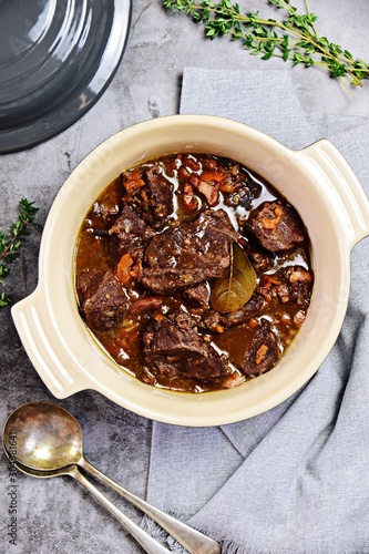 Beef bourguignon in the pot on the grey background, top view