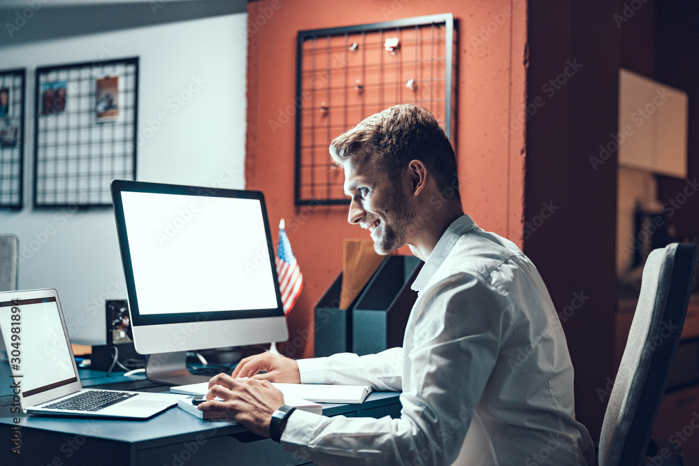 Happy male worker sitting in the workplace late at night Happy male worker sitting in the workplace late at night