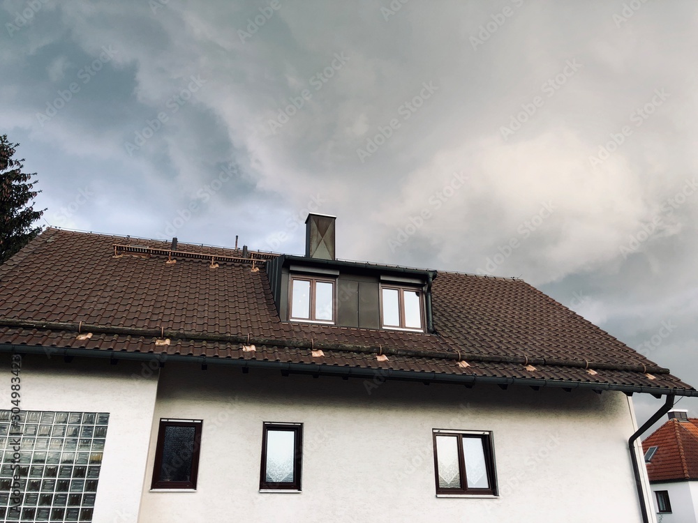 house with a roof and cloudy sky