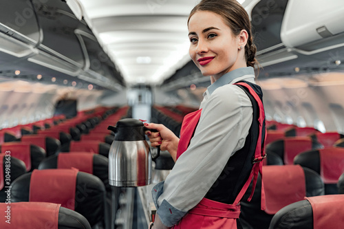Happy pretty stewardess is posing with teapot photo