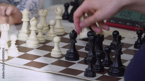 Coach teaches a child to play chess in a chess club. Explains which figure walks on the chessboard. Close-up view. 4k footage.