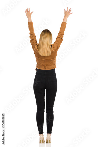 Young Woman Is Standing With Arms Raised. Rear View.