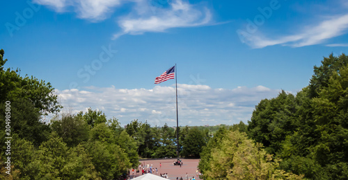 American flag flying high in statue of liberty park in Liberty Island.