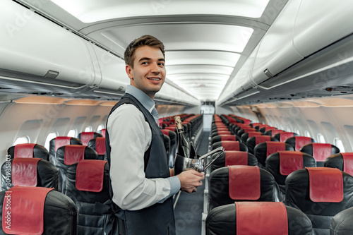 Smiling air steward is posing on camera in cabin