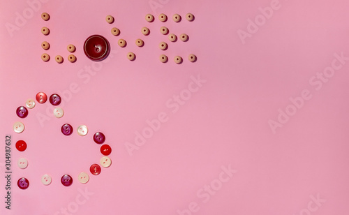 Composition for Valentine's Day February 14th. Button heart and the word love made of wooden beads on a pink background. Greeting card. Flat lay, top view, copy space.