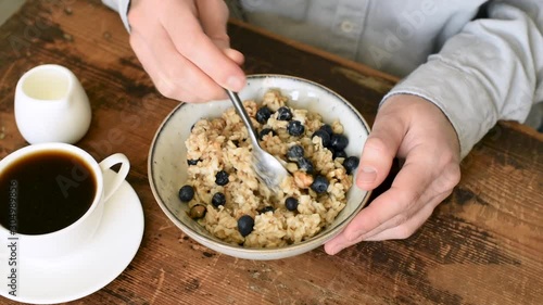 Person eating oatmeal porridge with blueberries for a healthy breakfast
