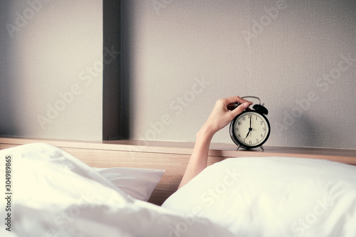 Woman sleep on the bed turns off the alarm clock wake up at the morning, Selective focus. photo