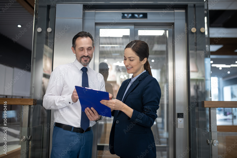 Couple of businessmen reading some reports while waiting for elevator Couple of businessmen reading some reports while waiting for elevator