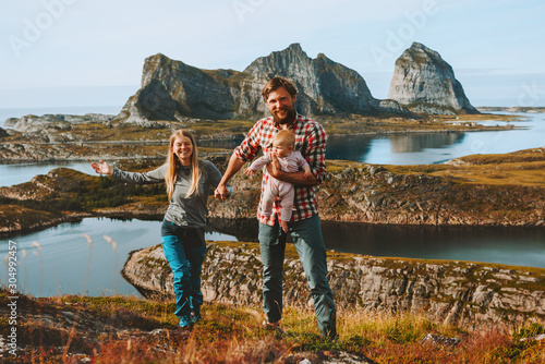 Happy family couple traveling with baby hiking outdoor healthy lifestyle active vacations mother and father parents with child adventure trip in Norway © EVERST
