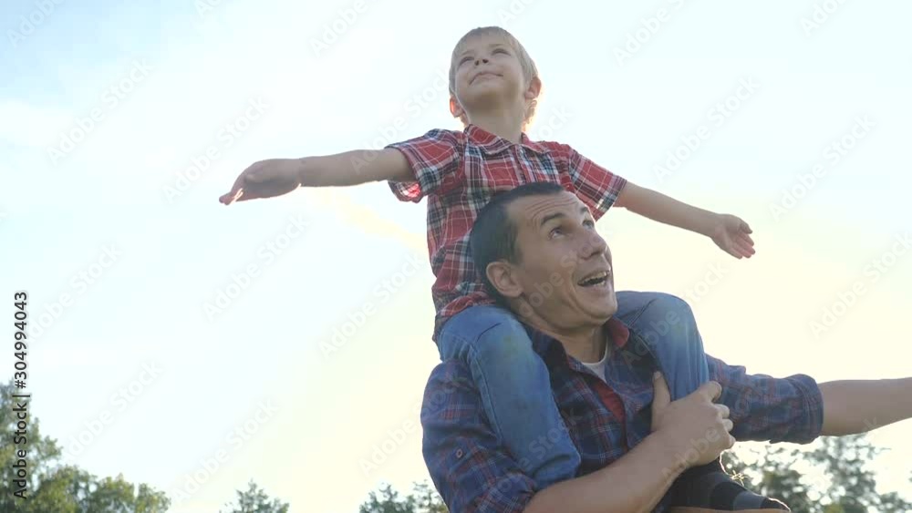 happy family father son concept. Father giving son ride on back lifestyle in nature outdoors .Portrait of happy father giving son ride on his shoulders and looking up. Cute boy with a dad playing happy family father son concept. Father giving son ride on back lifestyle in nature outdoors .Portrait of happy father giving son ride on his shoulders and looking up. Cute boy with a dad playing