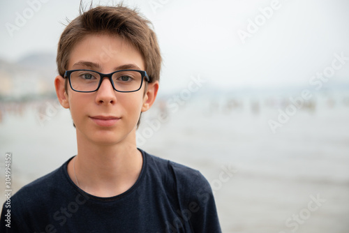 Handsome young boy at beach in Alicante. Beautiful calm smiling teen boy at Mediterranean sea coast in Spain. Travel, summer vacation, tourism, teenage lifestyle. photo