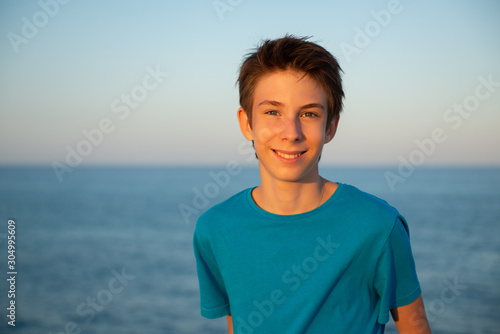 Handsome young boy at beach. Beautiful calm smiling teen boy at Mediterranean sea coast. Travel, summer vacation, tourism, teenage lifestyle.