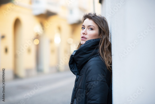 Young caucasian woman dressed in black clothes. Beautiful caucasian girl posing outdoor in Milan, Italy. Street fashion, winter outdoor