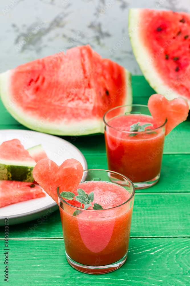 Fresh watermelon blended drink with mint leaves and a heart of watermelon in glasses on a wooden table Fresh watermelon blended drink with mint leaves and a heart of watermelon in glasses on a wooden table