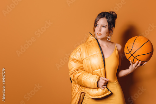 Fashionable young woman with ball on color background