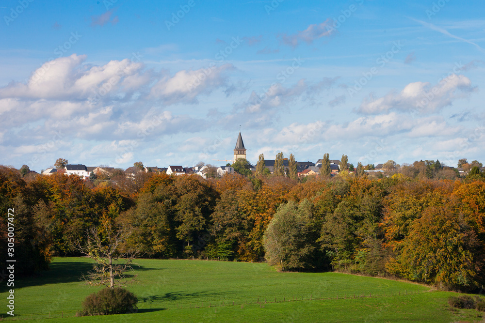 Obraz premium village of reisdorf in luxembourg under blue sky above fall forest