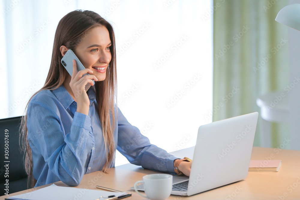 Beautiful young with laptop talking by mobile phone at table Beautiful young with laptop talking by mobile phone at table
