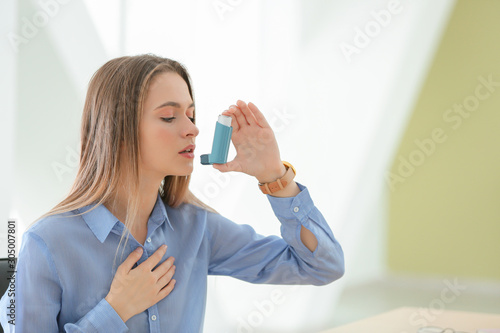 Young woman with inhaler having asthma attack in office