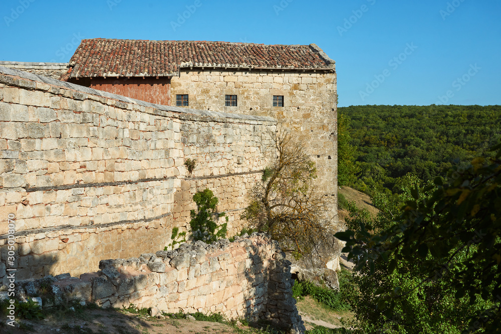 Old abandoned building with a stone wall. Stone house in the mountains. Sunny summer day, clear blue sky.