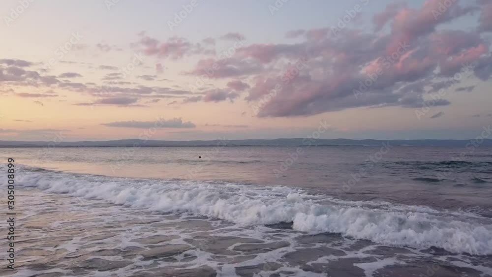 Aerial view of a sea surface with blue water waves under purple sunset sky. Aerial view of a sea surface with blue water waves under purple sunset sky.