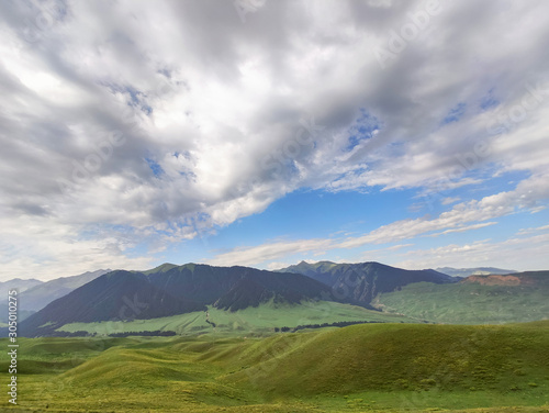 Mountain nature landscape with grassy green meadow on blue sky background