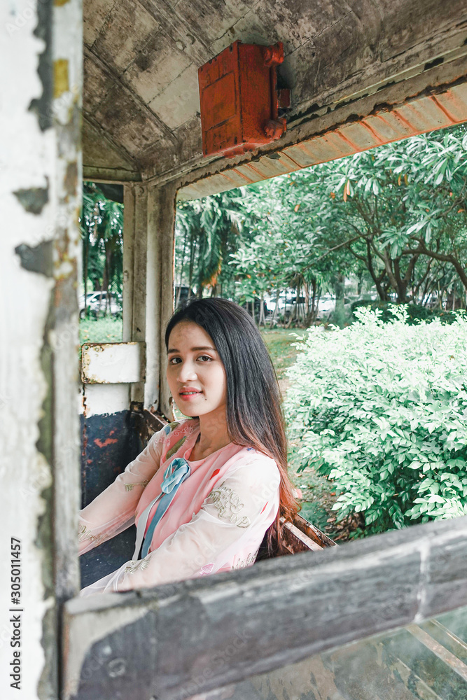 Young beautiful asian woman in pink dress relaxing with an old train
