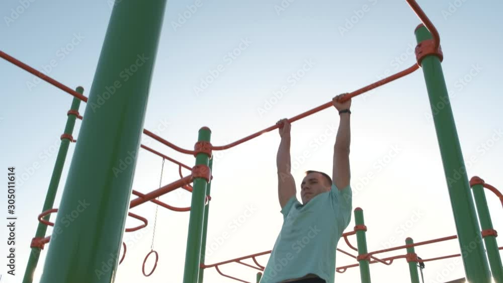 Young sports man with strong body training in active sports making pull up on the horizontal fitness bar outdoors. Young sports man with strong body training in active sports making pull up on the horizontal fitness bar outdoors.