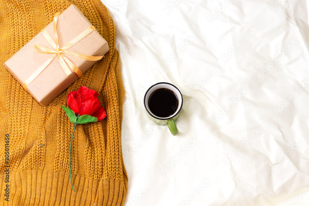 coffee cup above woolen scarf and red rose on bed, hello winter concept coffee cup above woolen scarf and red rose on bed, hello winter concept