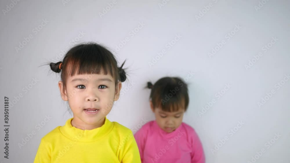 Portrait of a happy smiling Asian child girl and her older sister moody behind isolated on white background. Portrait of a happy smiling Asian child girl and her older sister moody behind isolated on white background.