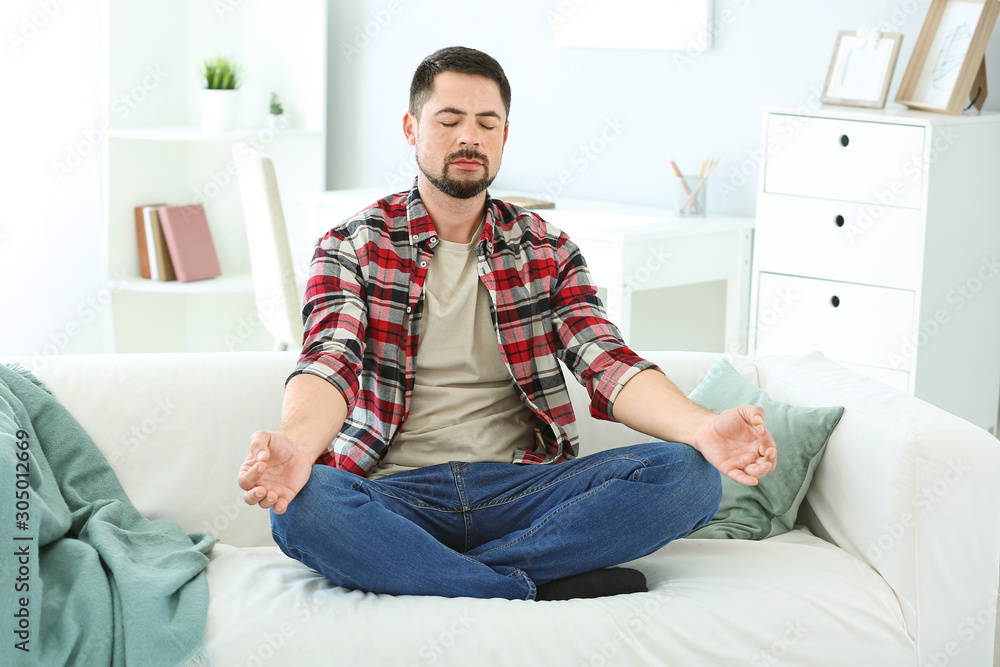Handsome man meditating at home