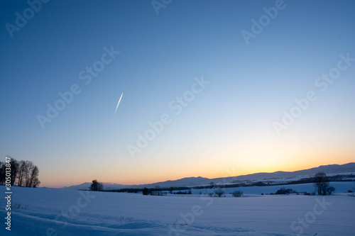 冬の夕暮れの空と飛行機雲 © kinpouge