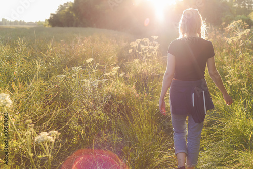 Obraz na plátně Young woman walking in the field at sunset