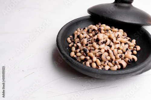 Cooked Fradinho beans in a black clay pot, isolated on a white background. photo