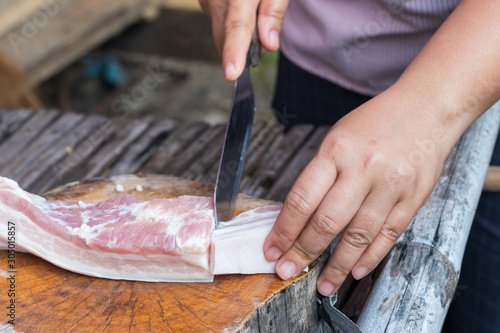 Fotografija Vendor used a knife slice the pork into pieces for sale.
