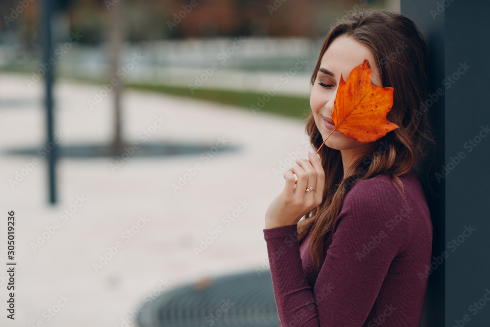 © primipil - Portrait of a young positive smiling woman with autumn yellow leaf
