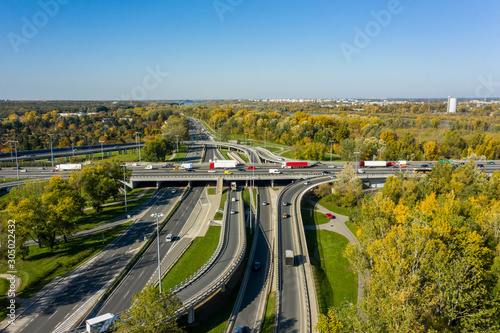 Aerial shot of a big freeway intersection in Warsaw, traffic going fast through many road flyovers. Warsaw, Poland. Drone shot at a highway with a clover junction with bridges and ramps, heavy traffic