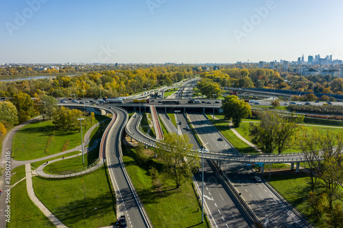 Drone shot at a highway with a clover junction with bridges and ramps, heavy traffic. Warsaw, Poland. Aerial view at the intersection of a large road in Warsaw, with traffic.