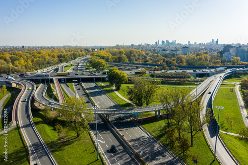 Aerial shot of a big freeway intersection in Warsaw, traffic going fast through many road flyovers. Warsaw, Poland. Drone shot at a highway with a clover junction with bridges and ramps, heavy traffic