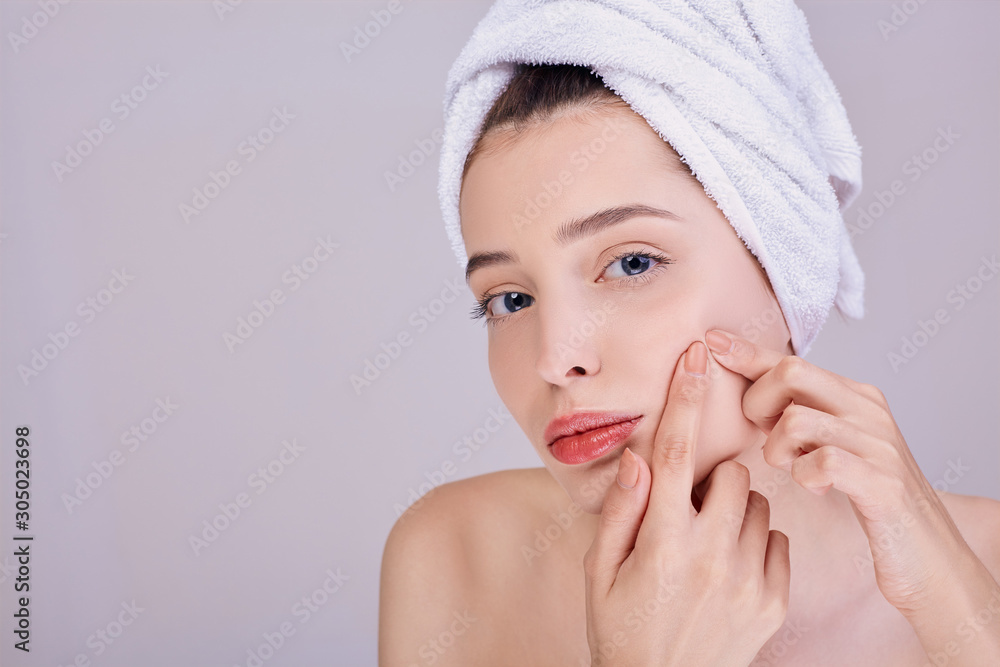 A half-naked woman presses a pimple on her left cheek. A half-naked woman presses a pimple on her left cheek.