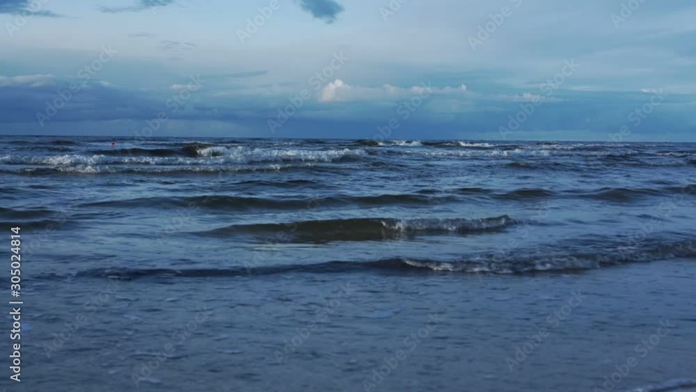 deep navy ocean with waves rolling on sand beach and creating white thick foam under amazing blue cloudy sky slow motion deep navy ocean with waves rolling on sand beach and creating white thick foam under amazing blue cloudy sky slow motion